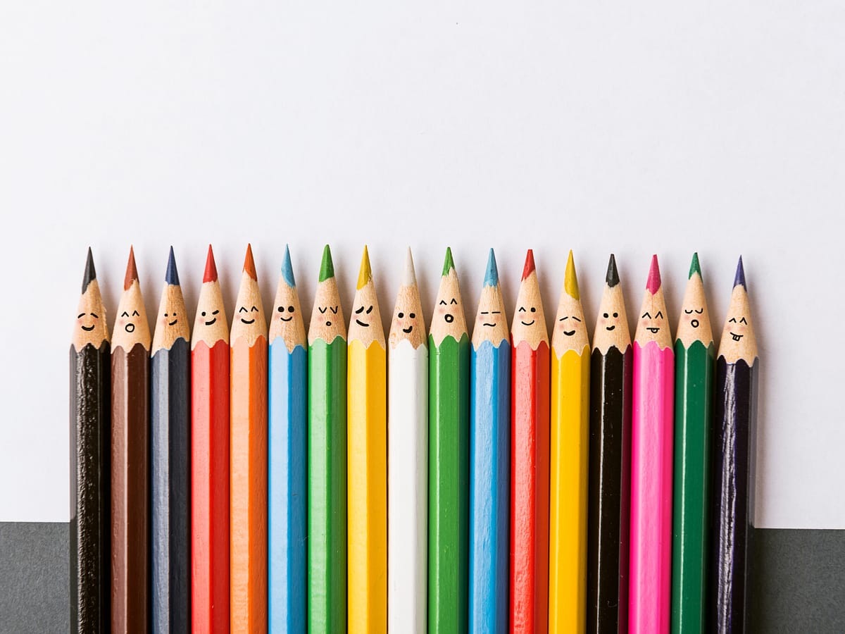 Buntstifte in vielen Farben mit Smileys, stellvertretend für Diversity