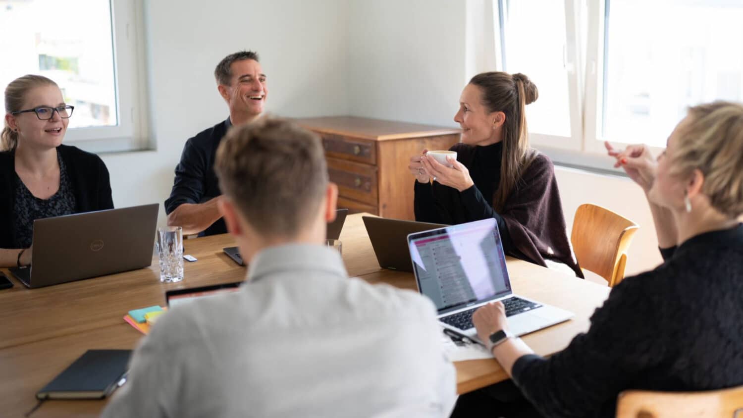 Lachende Menschen versammelt um Tisch mit Laptops 